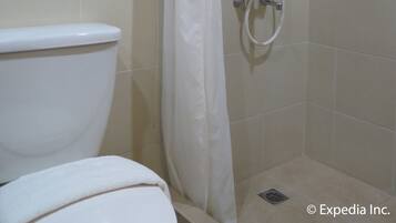 A bathroom with a shower, toilet, and a tiled floor.