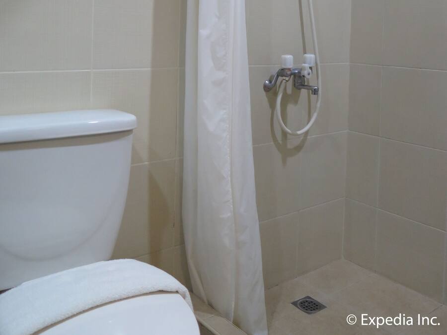 A bathroom with a shower, toilet, and a tiled floor.