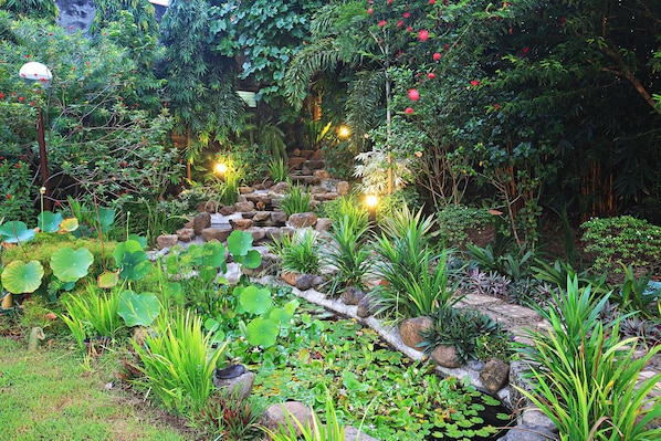 A lush garden with a variety of plants, a stone pathway, and decorative lighting.