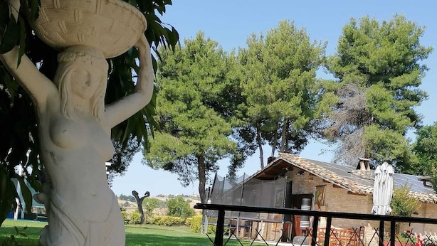 Une statue d’une femme dans un jardin, avec un bâtiment en arrière-plan.