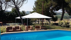 Une piscine avec des chaises longues et un espace salon abrité.
