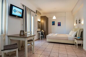 Habitación de hotel con cama, escritorio, silla, televisor y baño.