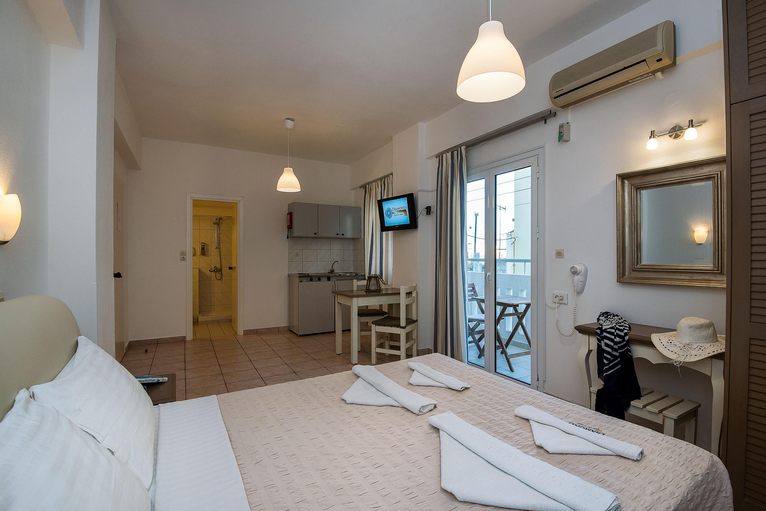A hotel room with a bed, a desk, a TV, and a balcony with a view.