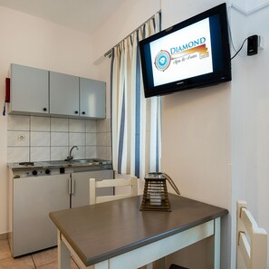Una cocina con estufa integrada, pileta y televisor montado en la pared mostrando un logotipo.