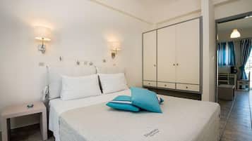 A bedroom with a bed, nightstands, wall-mounted lamps, a wardrobe, and a view of the adjacent room.