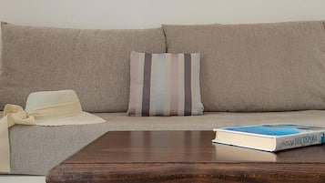 A living room with a beige sofa, striped pillow, and a book on the coffee table.