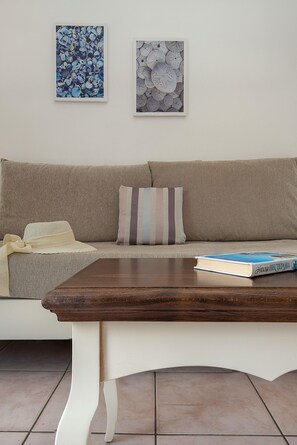 A living room with a beige sofa, striped pillow, and a book on the coffee table. - Diamond Apts and Suites (Hersonissos)