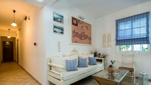 A living room with a white sofa, a glass coffee table, and a blue window blind. - Diamond Apts and Suites (Hersonissos)