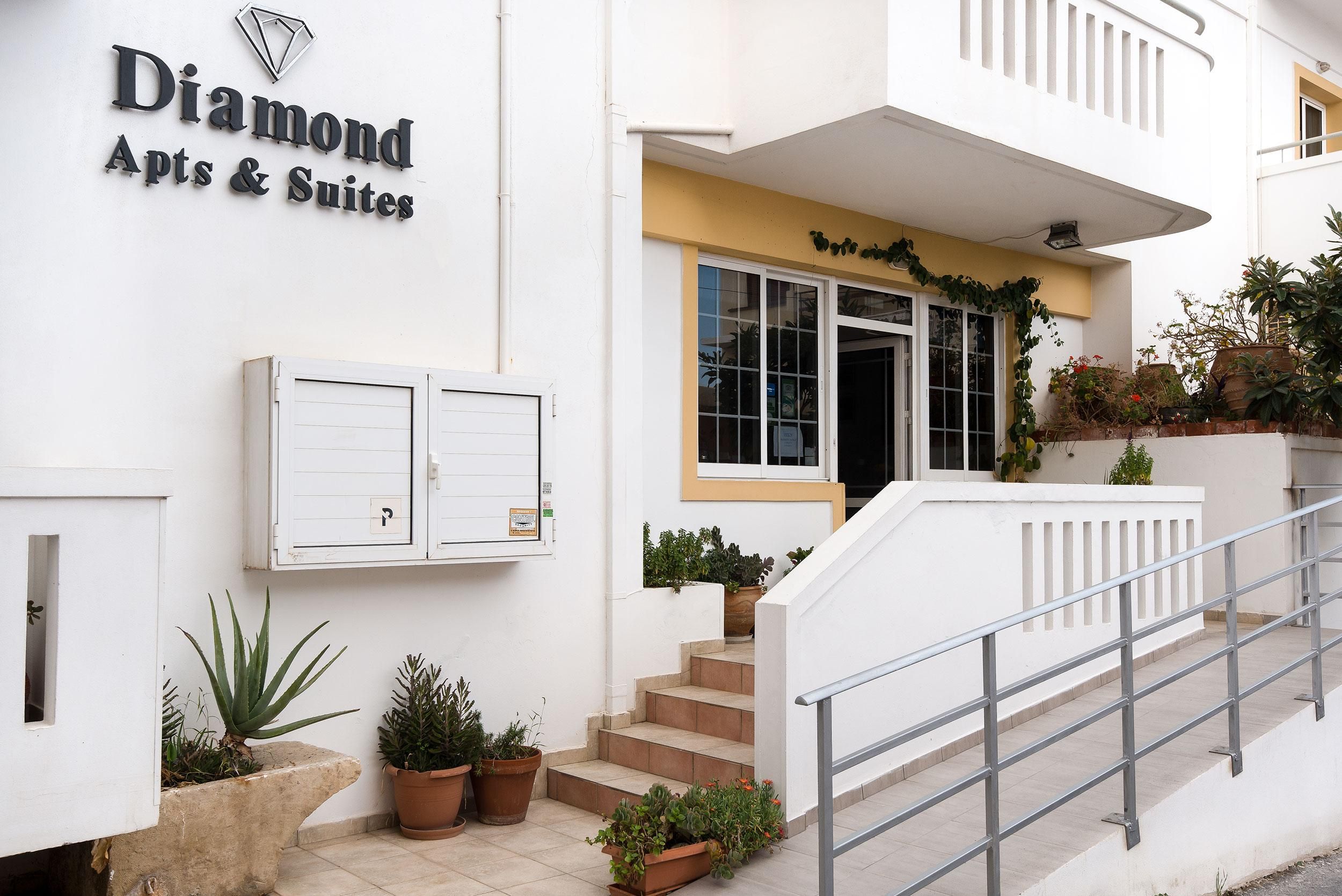 A building with a sign reading 'Diamond Apts & Suites' and a staircase leading to the entrance.