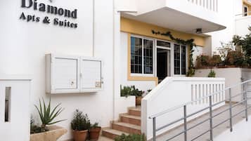A building with a sign reading 'Diamond Apts & Suites' and a staircase leading to the entrance.