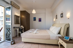 A hotel room with a bed, a desk, a chair, a window, and a door. - Diamond Apts and Suites (Hersonissos)