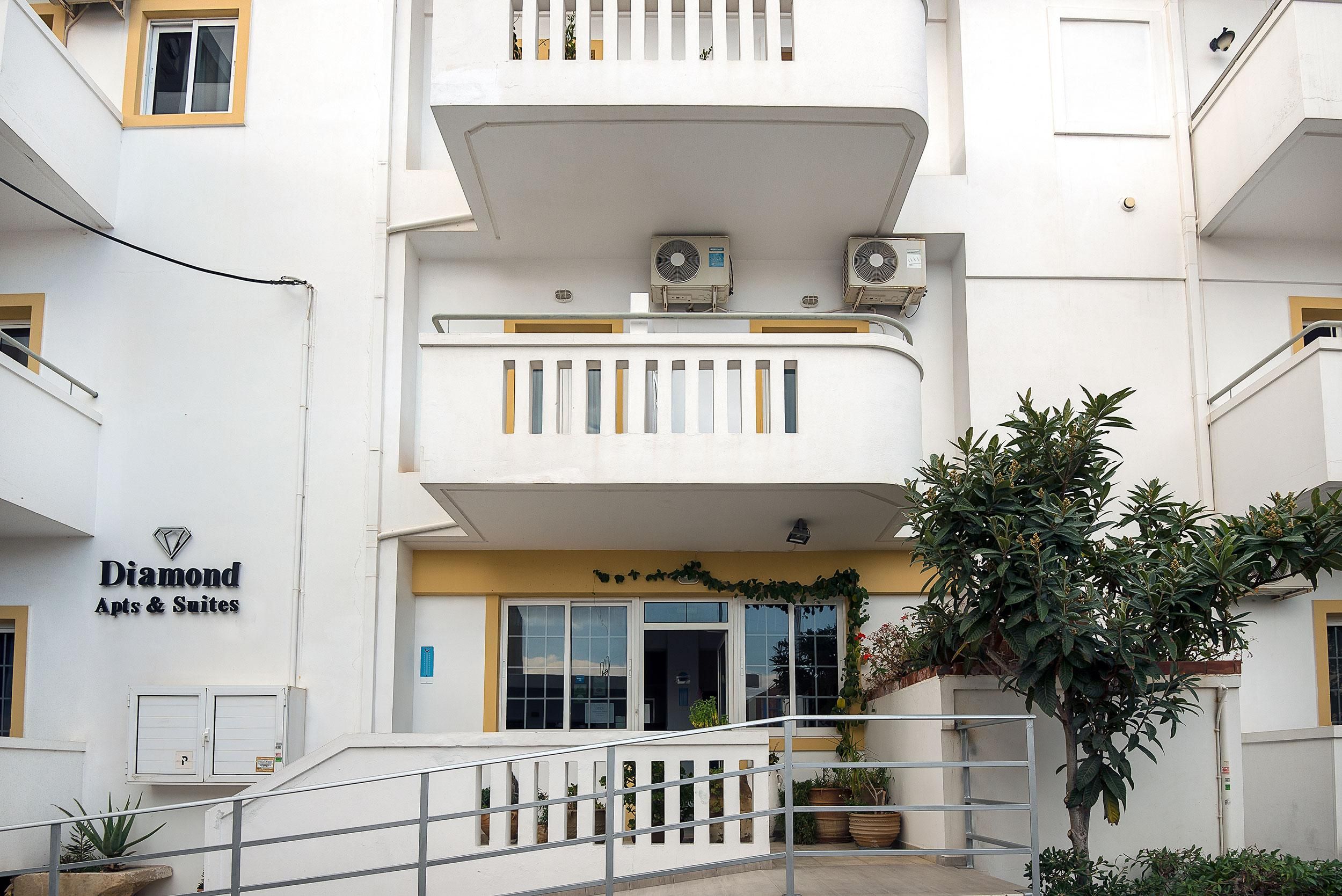 Un edificio con un cartel que dice 'Diamond Apts & Suites' y una escalera que lleva a la entrada.