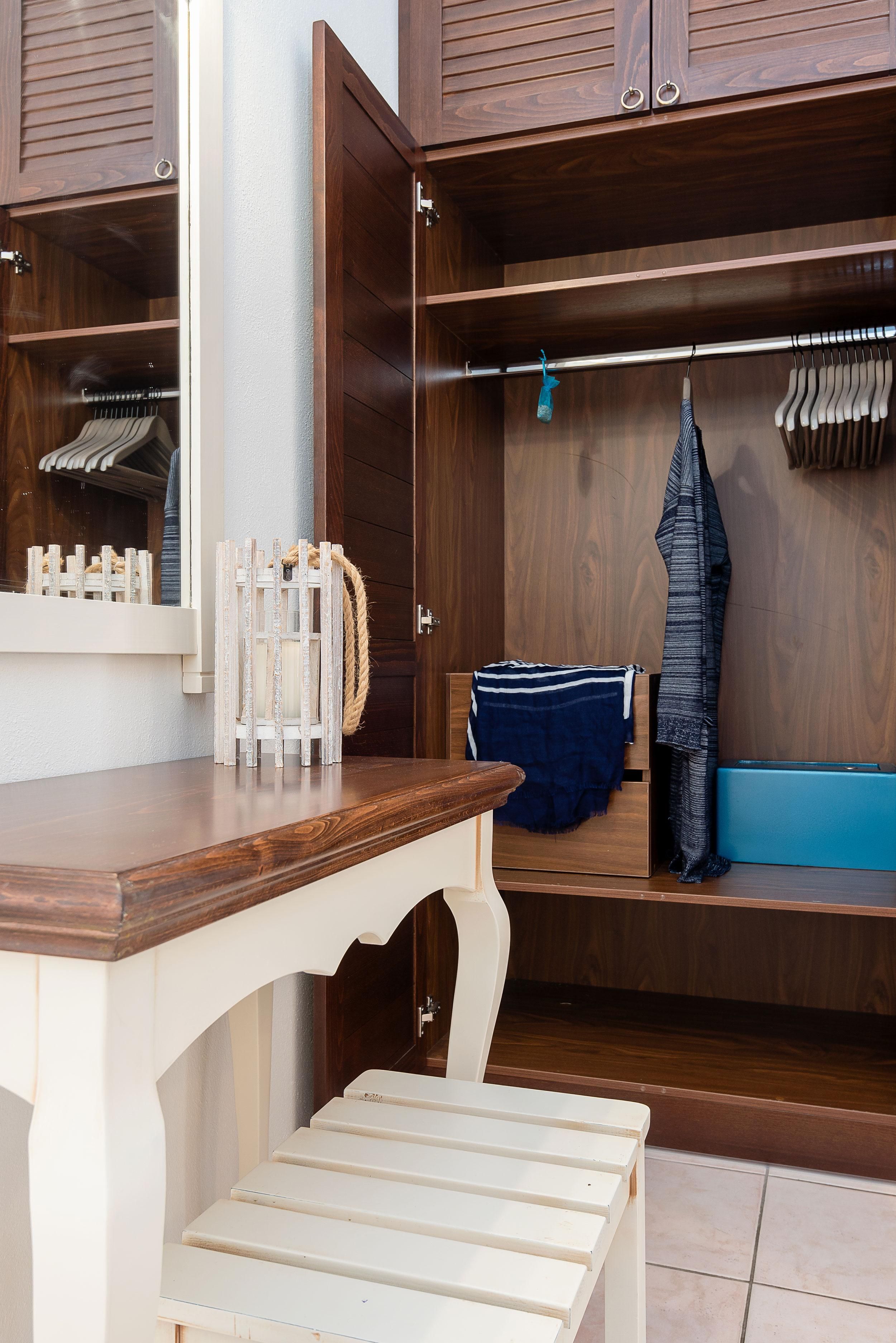 Ein Holzschrank mit Kleiderstange, einem Kleiderhaken und einer Bank.