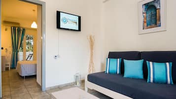 A modern living room with a sofa, a television mounted on the wall, and a framed painting.