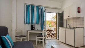 A compact living space with a kitchenette, a dining area, and a sofa with a cushion. - Diamond Apts and Suites (Hersonissos)