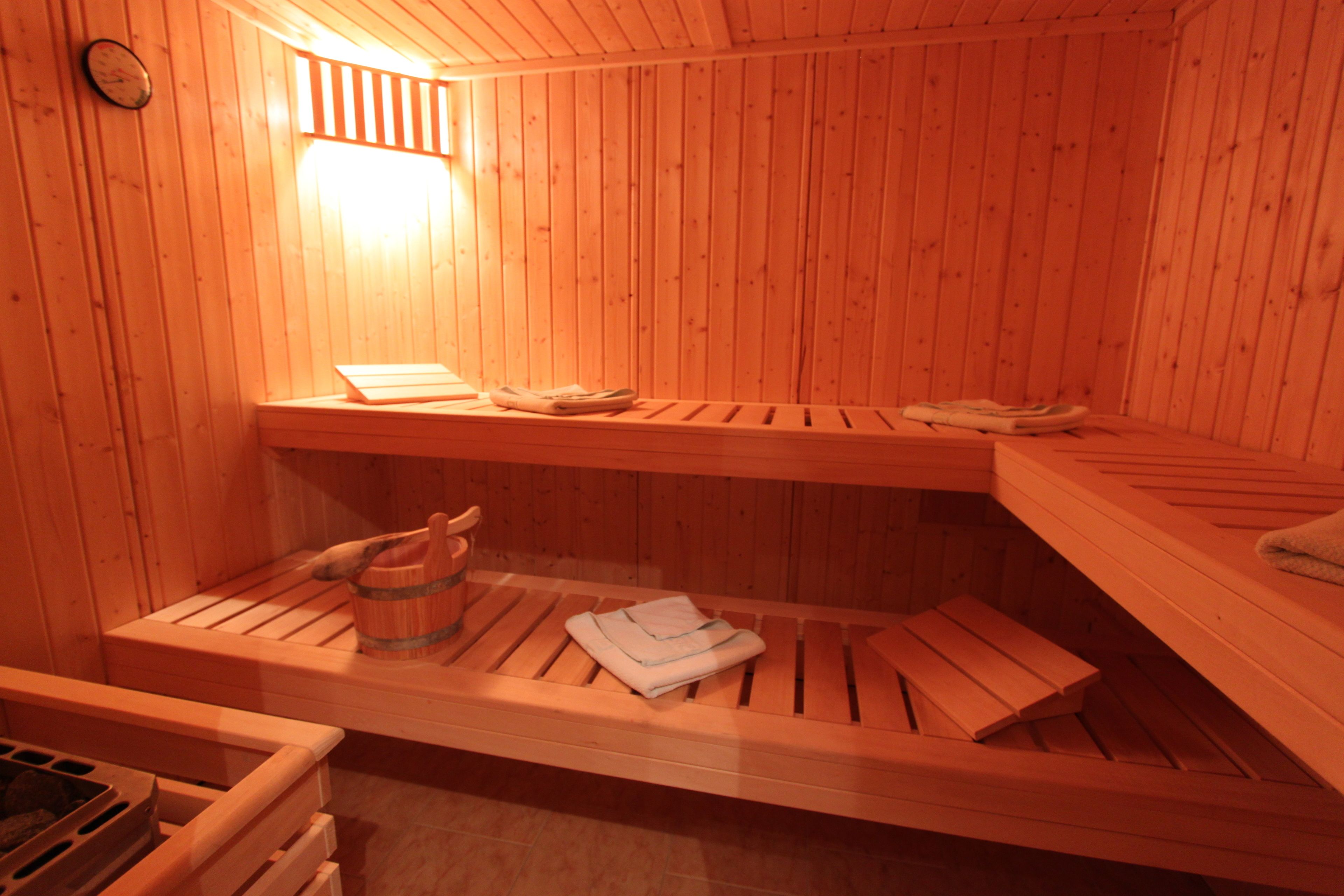 Un sauna avec des bancs en bois et un banc muni d’un seau.