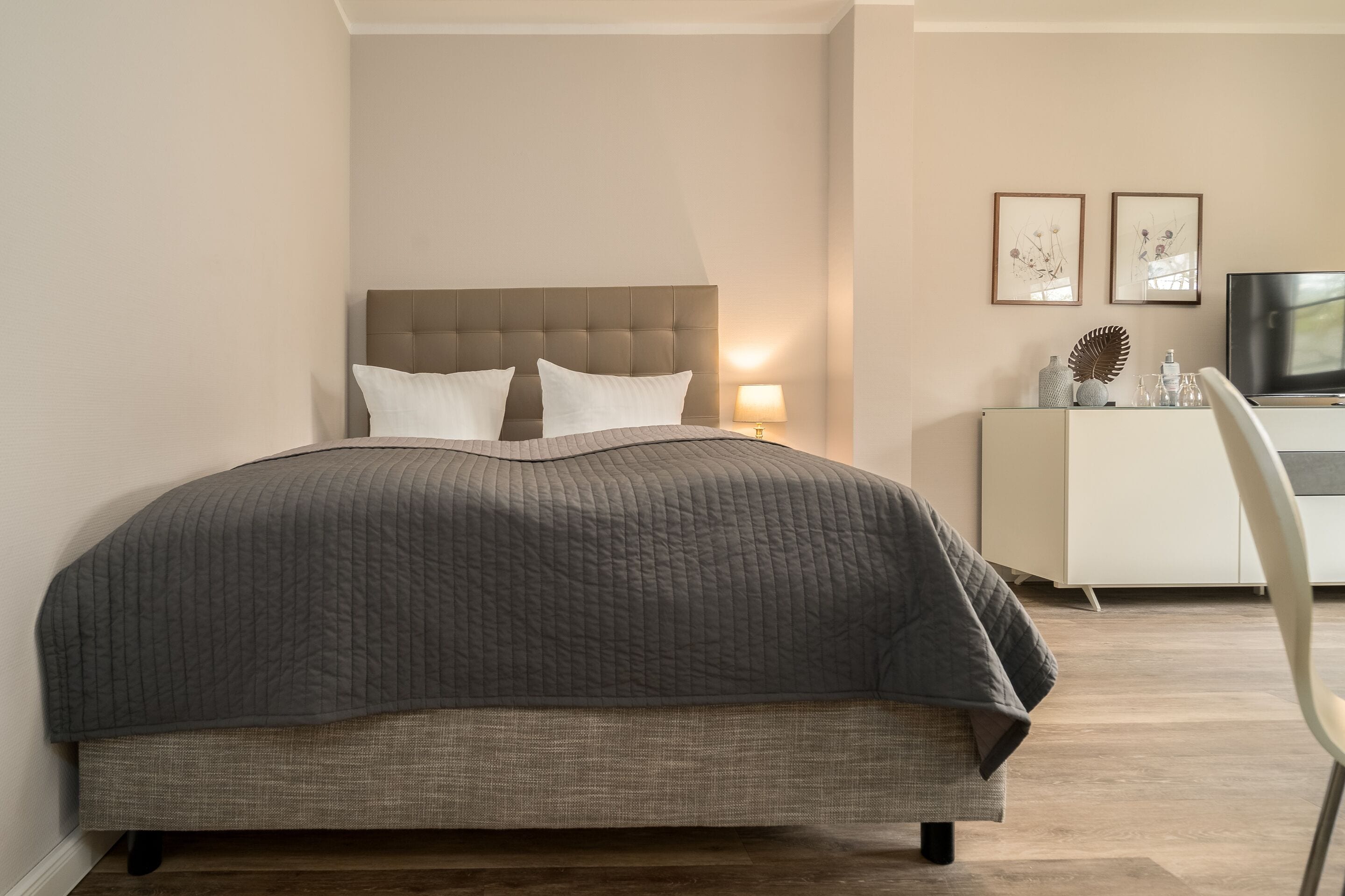 Een slaapkamer met een groot bed, een nachtkastje, een lamp en een televisie.