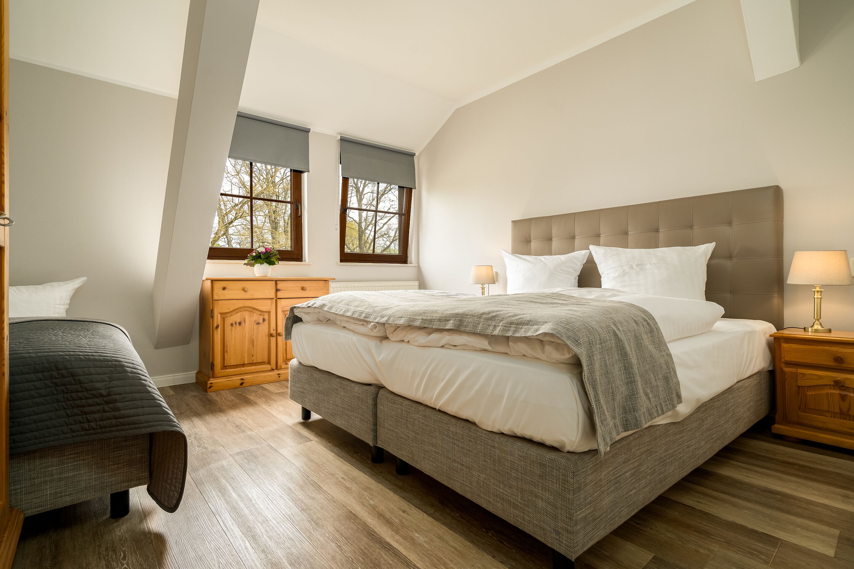 Une chambre à coucher avec un grand lit, une table de chevet, une commode en bois et un banc.