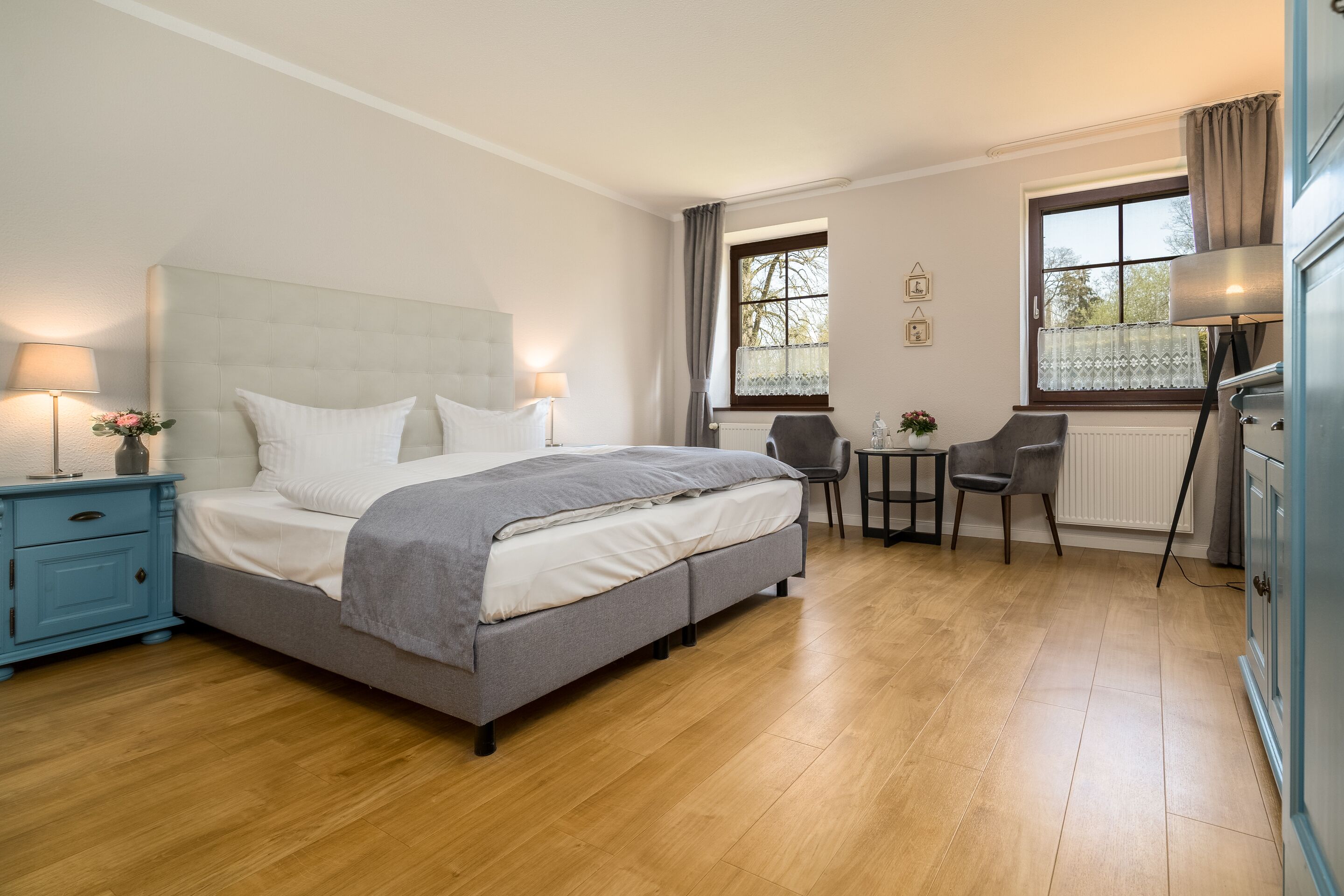 Ein Schlafzimmer mit einem Bett, Nachttischen, einem Schreibtisch, einem Stuhl und einem Fenster.