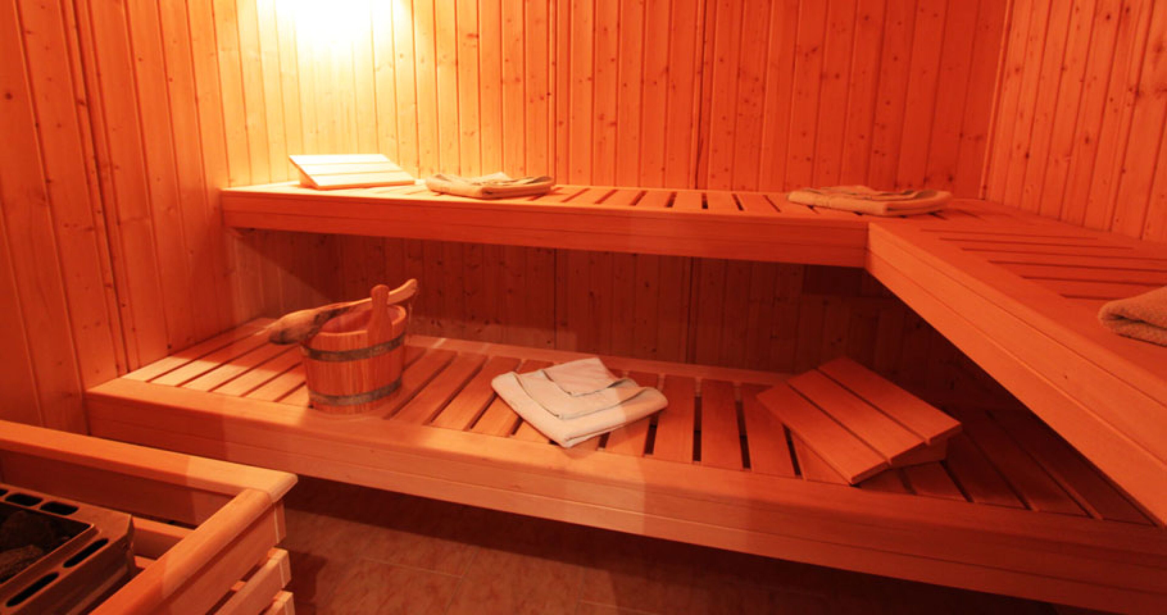 Een houten sauna met banken en een houten emmer.