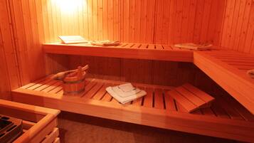 Een houten sauna met banken en een houten emmer.