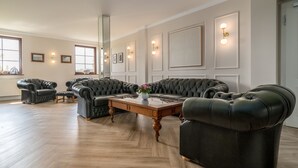Een ruime woonkamer met een grote hoekbank, een houten salontafel en een groot raam dat voor natuurlijk licht zorgt.