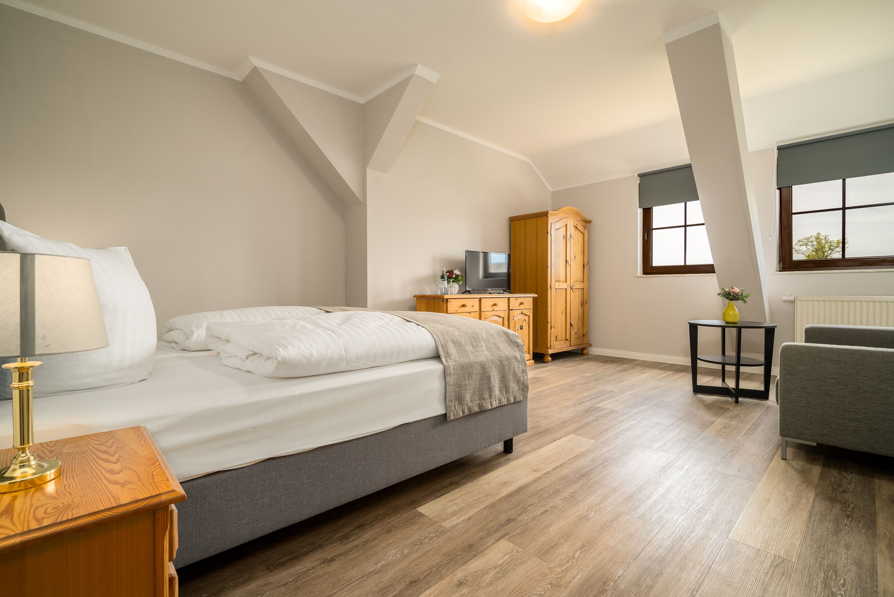 Un dormitorio con cama, mesita de noche, cómoda, televisor y ventana.