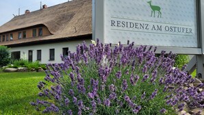 Een bord met 'RESIDENZ AM OSTUFER', met een rieten dakgebouw op de achtergrond.