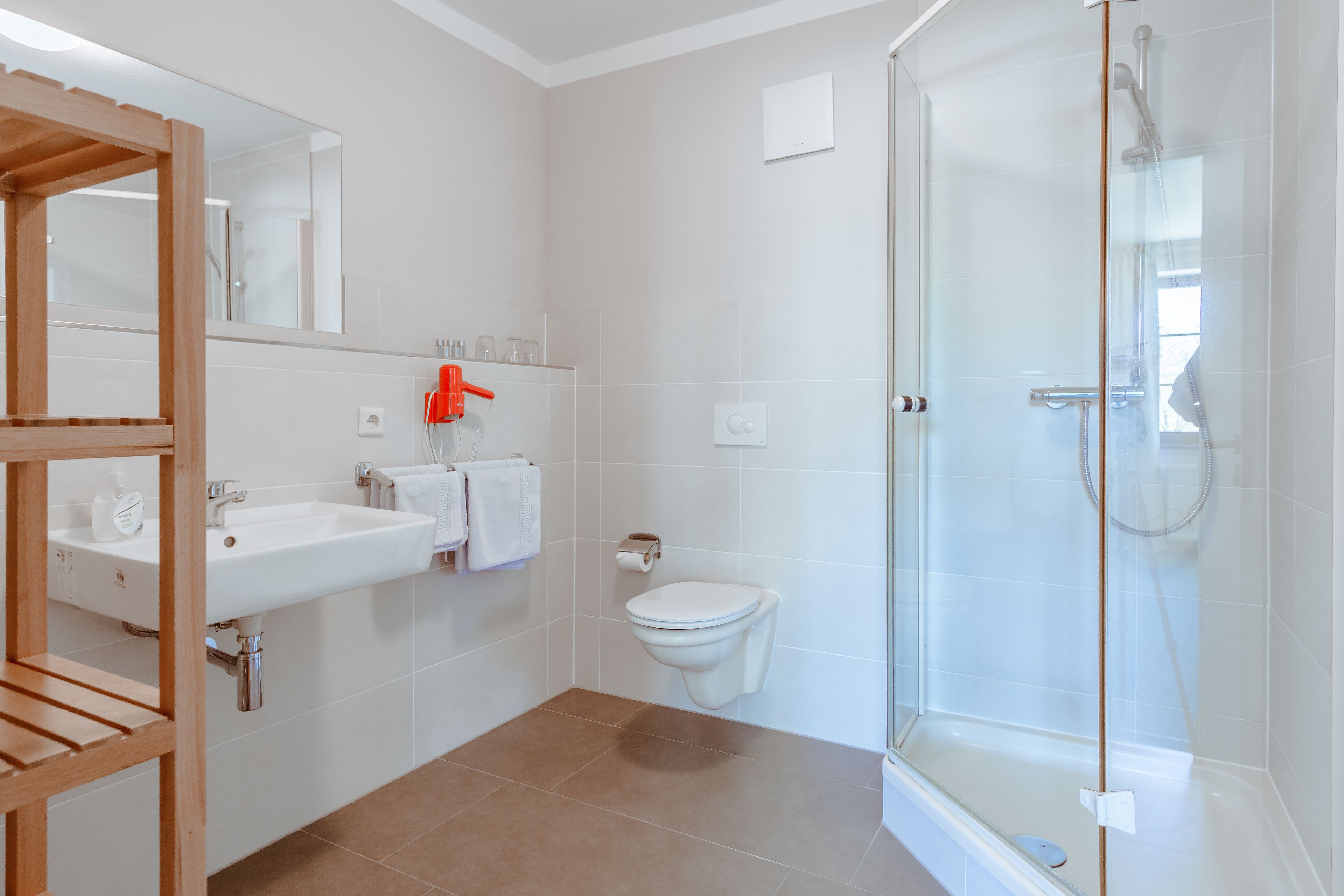A modern bathroom with a glass shower enclosure, a wooden vanity, and a white sink.