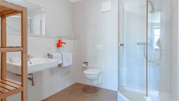 A modern bathroom with a glass shower enclosure, a wooden vanity, and a white sink.