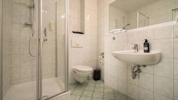 A modern bathroom with a glass-enclosed shower, a toilet, and a sink with a mirror above it.