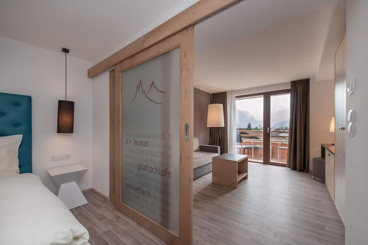 Un hotel moderno con una cama grande, una puerta corredera de madera, un escritorio y vistas a las montañas.