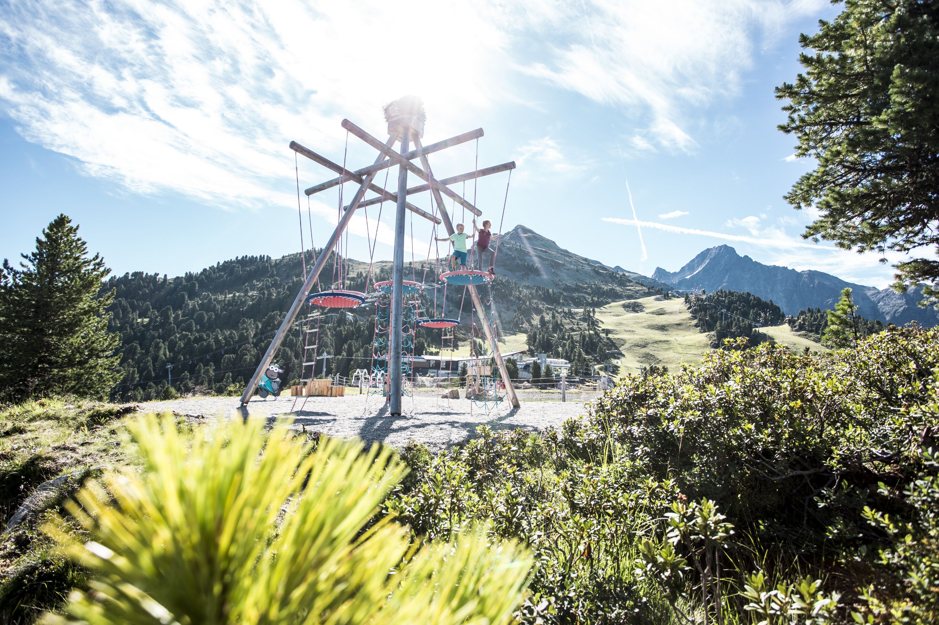 A playground with swings and climbing structures in a mountainous area.