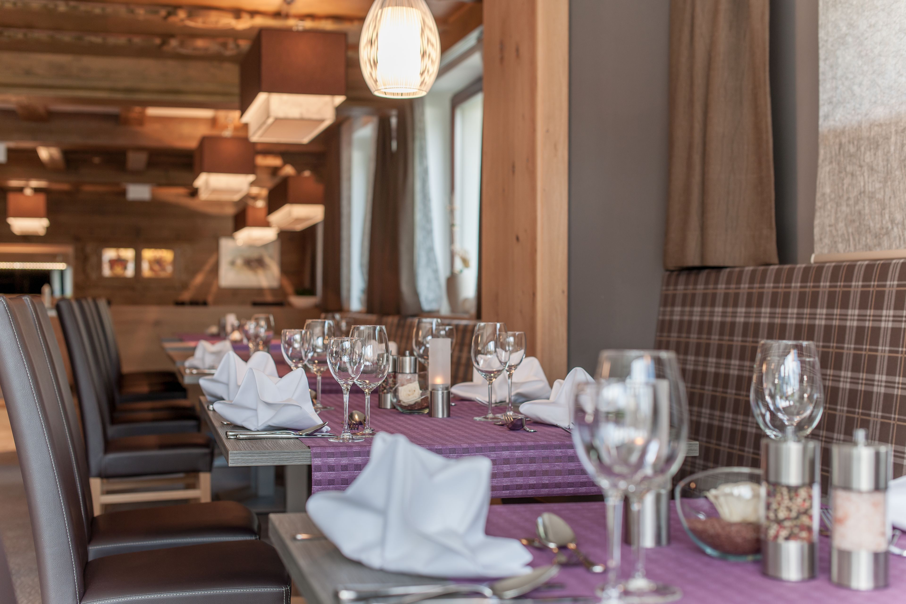 A restaurant with a long table set for a meal, featuring neatly arranged plates, glasses, and cutlery.