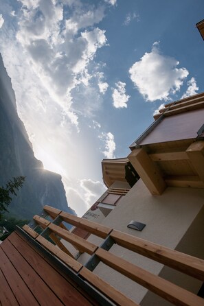 Una terraza de madera con un paisaje de montaña y un edificio que muestra el letrero "BERGWEITET".