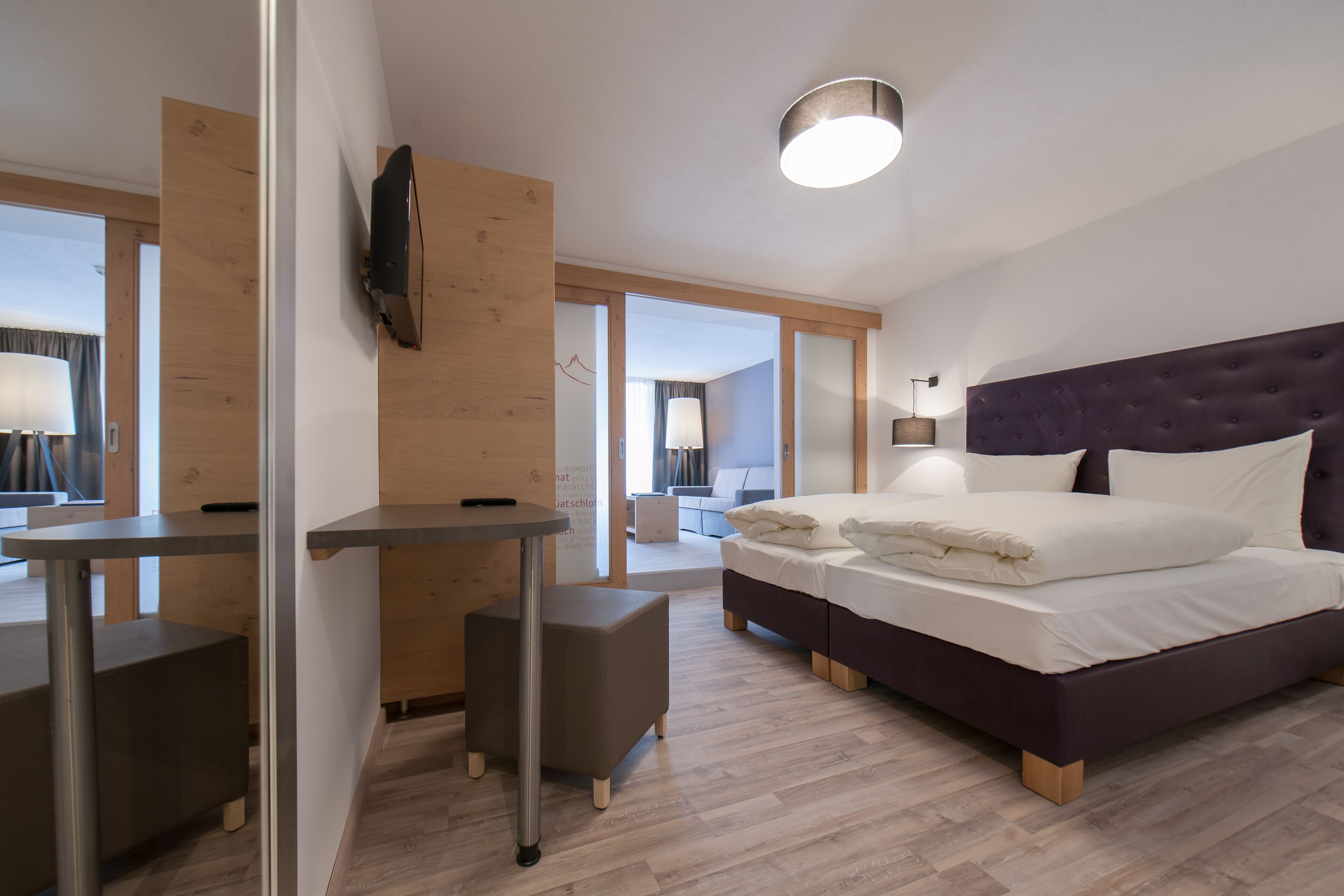 A modern hotel room with a bed, a desk, and a chair.