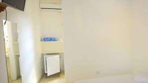 A hotel room with a bed, a television mounted on the wall, a small refrigerator, and a bathroom visible through an open door. - Pousada Praia do Jabaquara (Paraty)