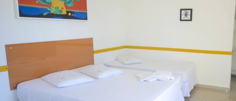 Una habitación de hotel con una cama, dos almohadas, un cuadro en la pared y una fotografía enmarcada.