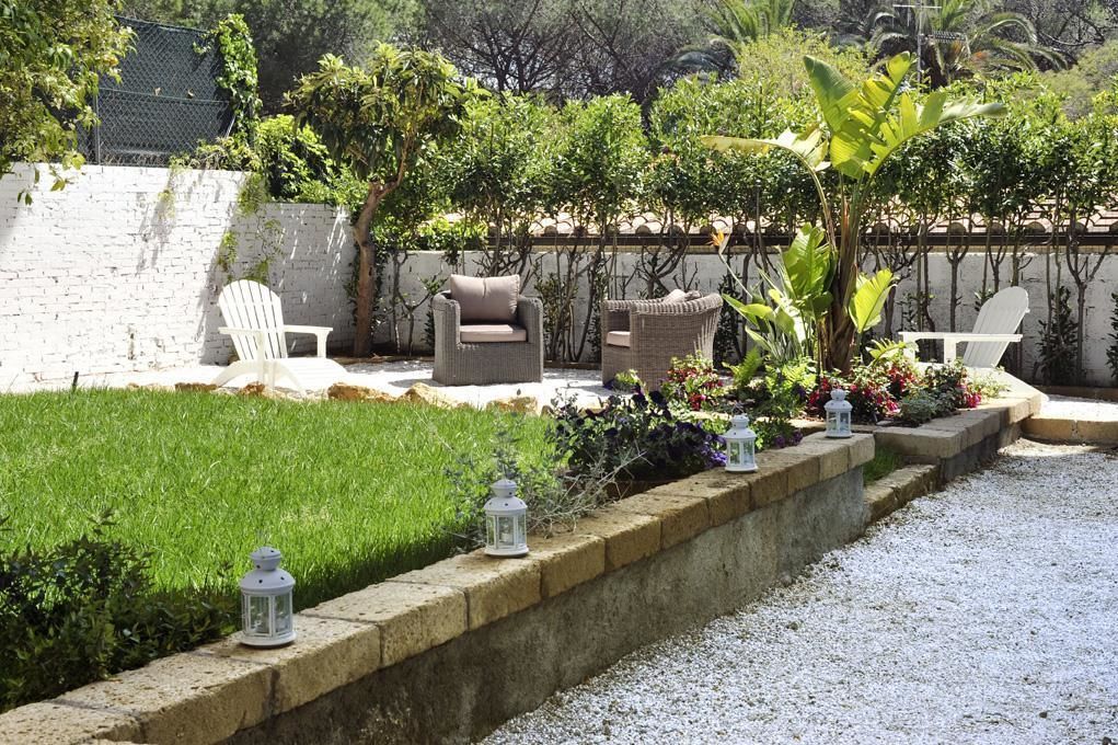 A patio with outdoor seating, a well-maintained lawn, and a stone border with lanterns.
