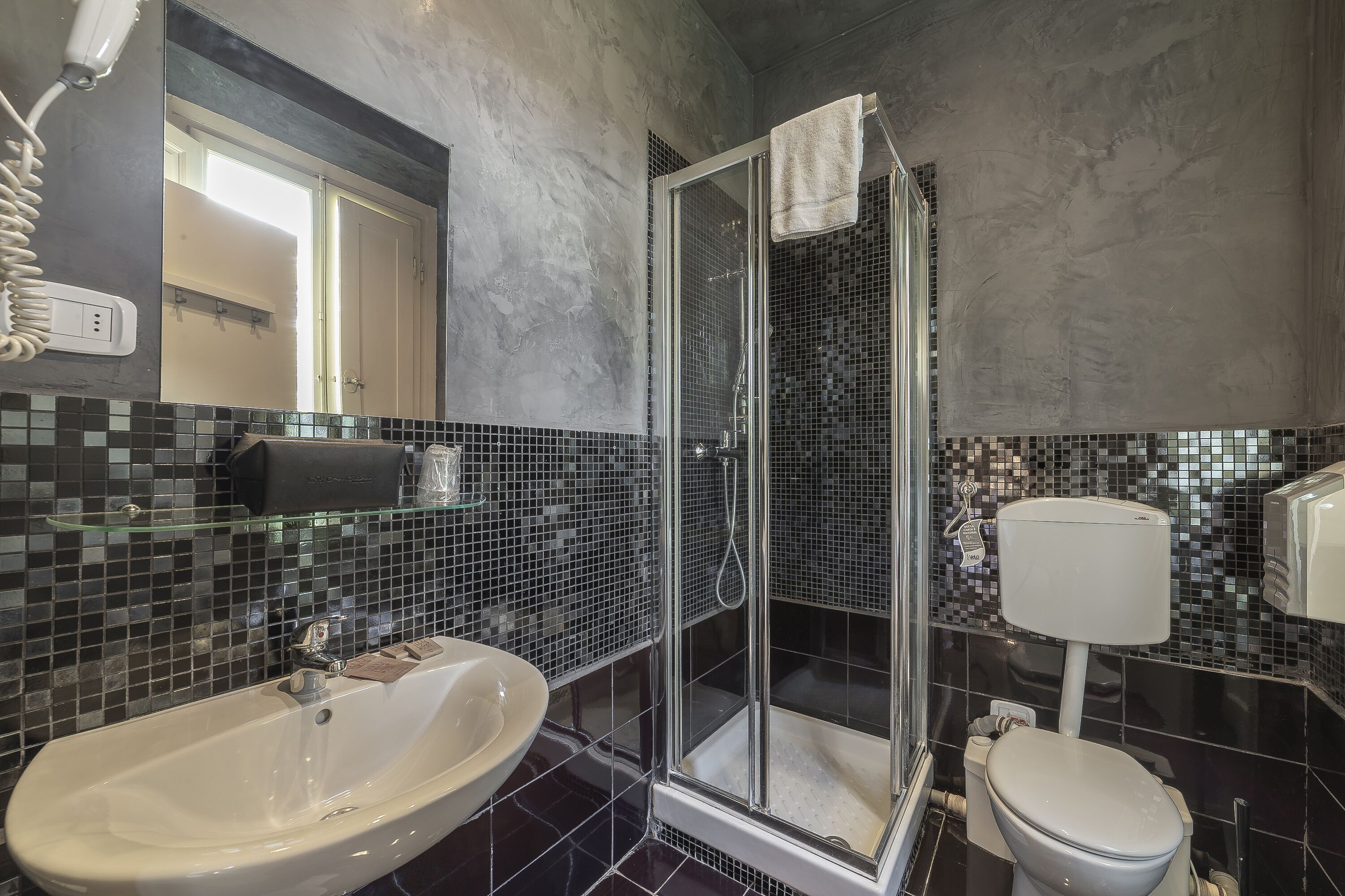 Un baño con ducha de vidrio, un lavabo blanco y un inodoro.