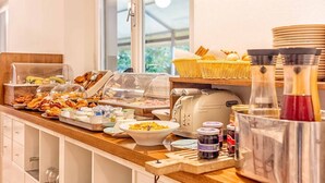 A breakfast buffet with various food items, a toaster, and condiments. - Guerrini Hotel (Rosignano Marittimo)