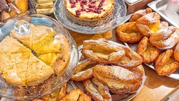 A variety of baked goods including pies, pastries, and bread displayed on a wooden table.