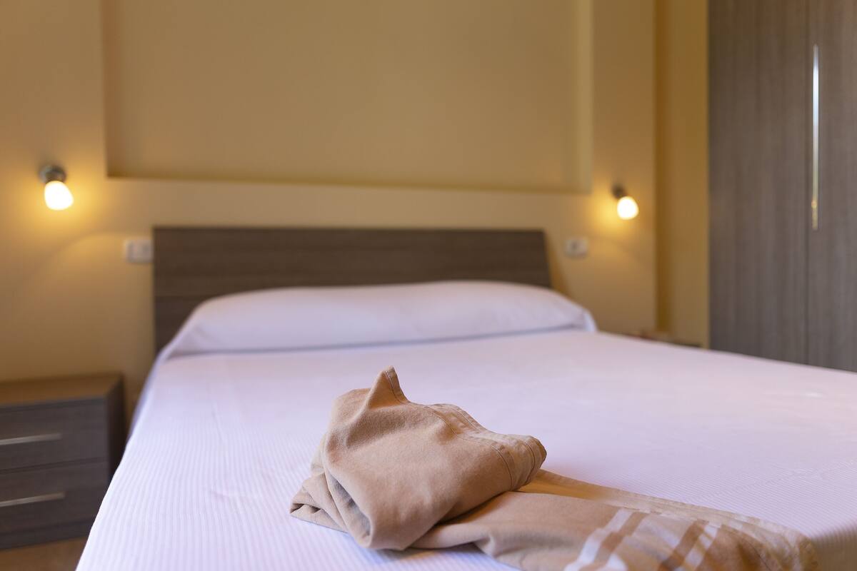 Una cama bien tendida con un edredón doblado y un cabecero.