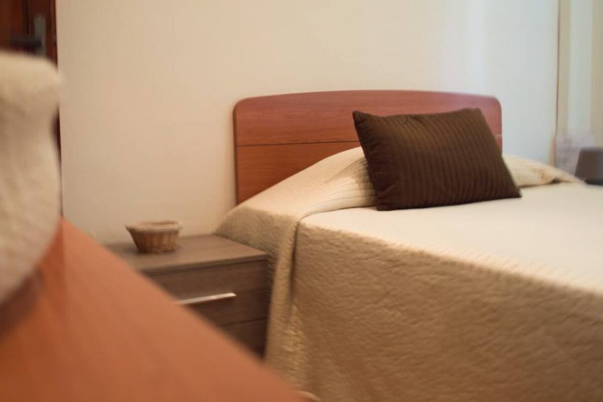 Una habitación de hotel con una cama, una mesita de noche y una pequeña mesa con una taza.