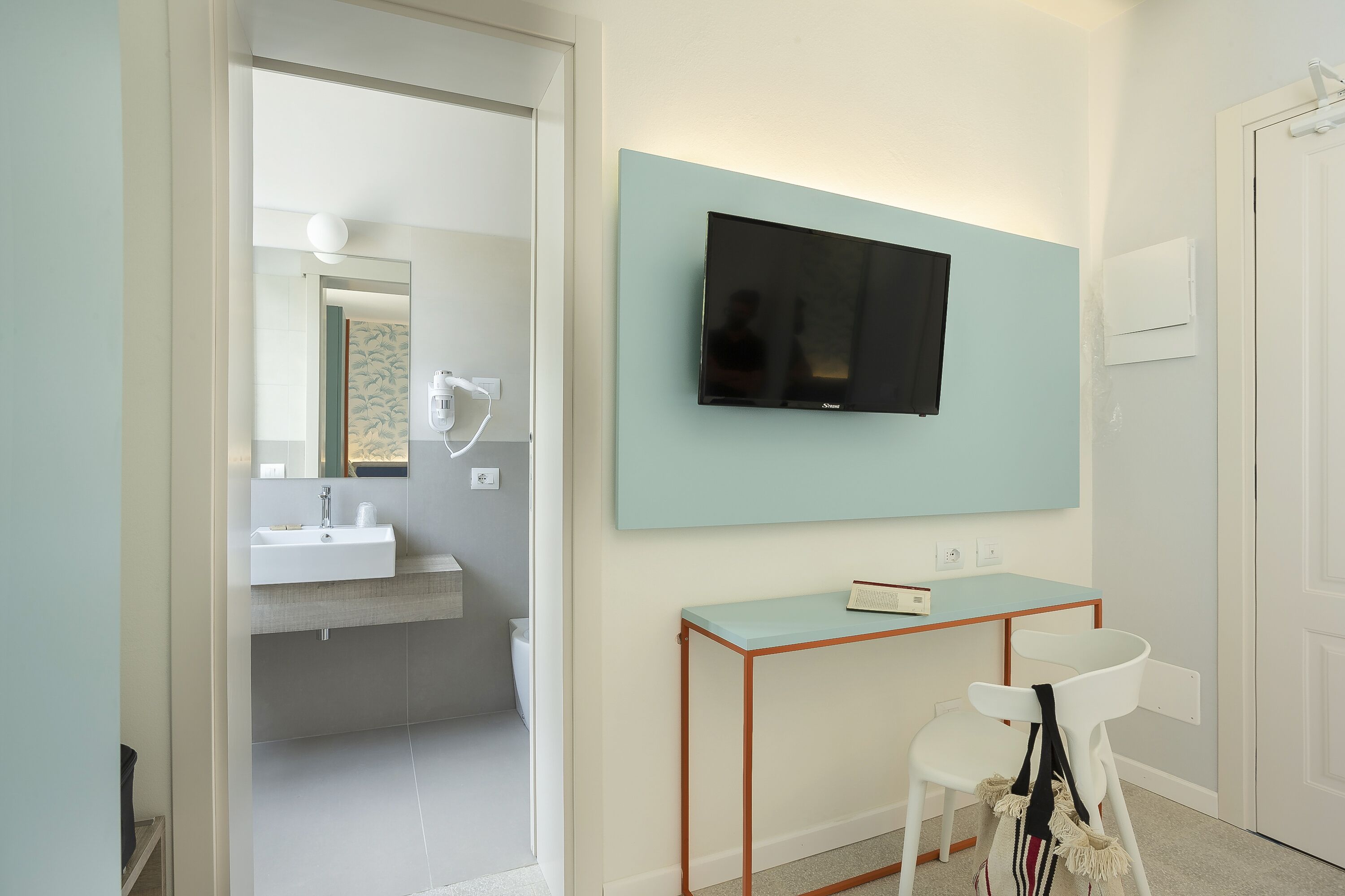Een moderne badkamer met een wastafel, spiegel en een televisie aan de muur.