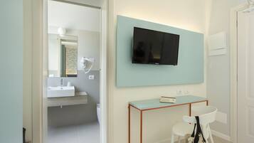 Een moderne badkamer met een wastafel, spiegel en een televisie aan de muur.