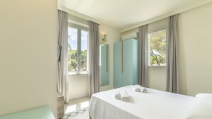 A hotel room with a bed, a small table, a wardrobe, and a window with curtains. - Guerrini Hotel (Rosignano Marittimo)