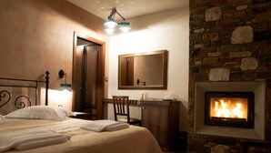 A hotel room with a bed, a desk, a chair, a fireplace, and a mirror. - Belina Hotel (Volos)
