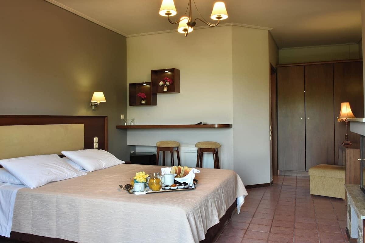 A hotel room with a bed, bedside tables, a small kitchenette, and a seating area.