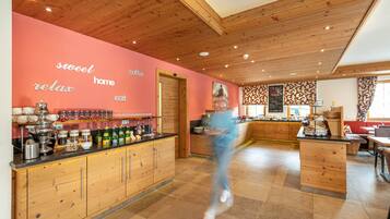 A modern kitchen with wooden cabinets, a black countertop, and a pink wall with motivational words.
